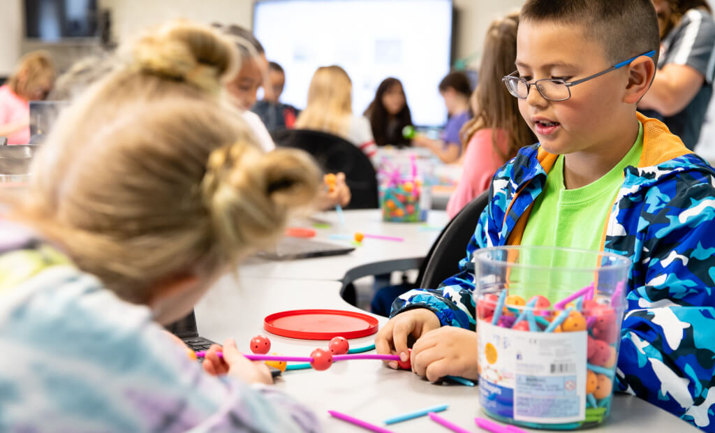 little boy wearing glasses playing at a table with a little girl with blonde hair