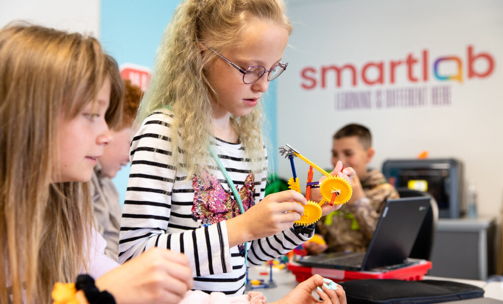 a child with glasses and blonde hair plays with building toys in a smartlab setting